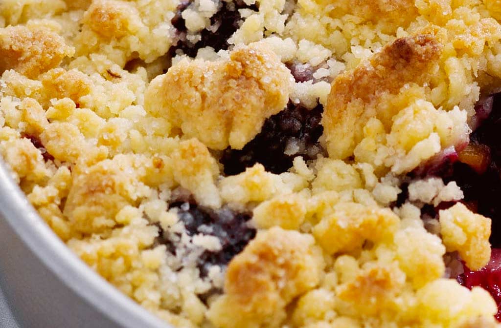 Airfryer recept: zwarte bessen en abrikozen crumble taart in een witte schaal